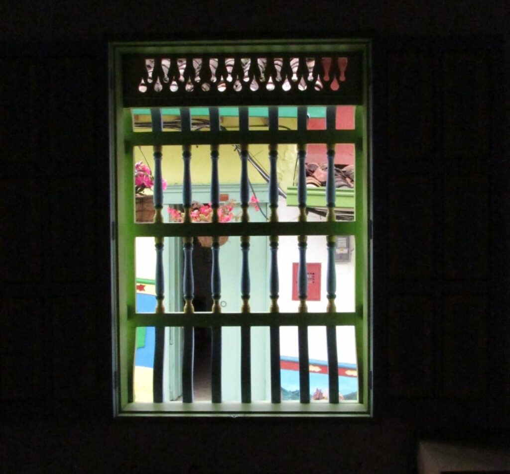 Una puerta se ve desde dentro de una case de Guatapé, a través de una ventana