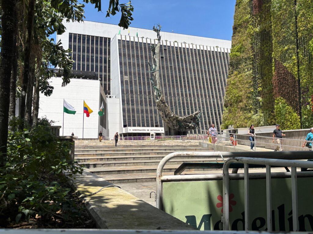 Delante de las banderas de Antioquia, Colombia y Medellín, algunos votantes salen del puesto de votación en la Alpujarra.