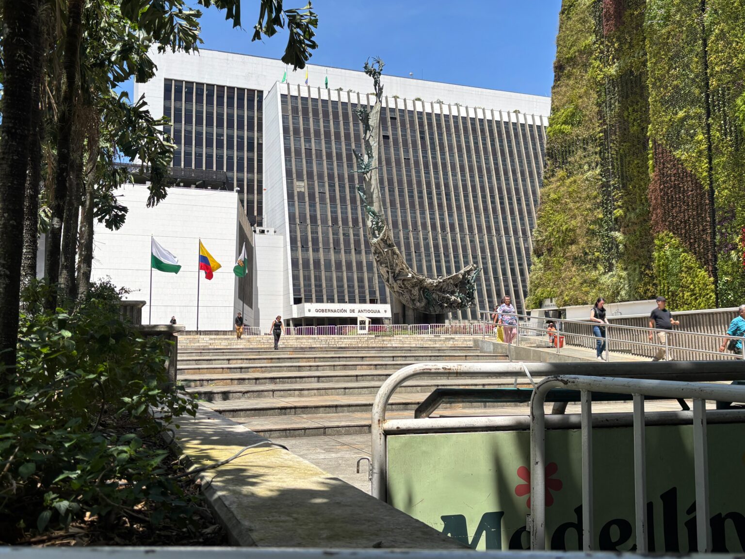 Delante de las banderas de Antioquia, Colombia y Medellín, algunos votantes salen del puesto de votación en la Alpujarra.